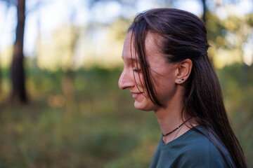 Close-up profile portrait of a smiling young woman outdoors with blurred background © WoodHunt