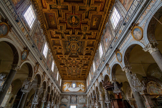 Ornate gilded coffered ceiling inside a grand Italian basilica with frescoes and chandeliers