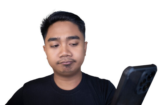 Doubtful and unimpressed Indonesian man in a black t-shirt looking down at his smartphone with a skeptical expression against a white background.