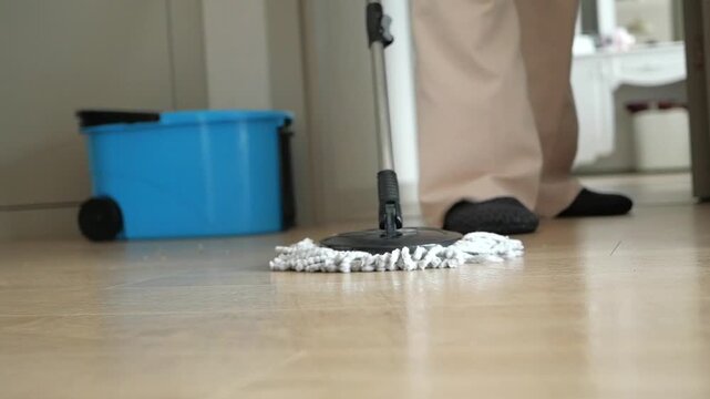 Person cleaning floor with a mop and bucket, close up shot from floor level