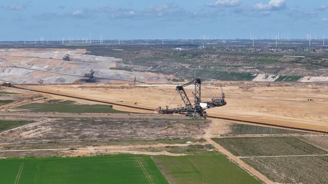 second bucket wheel excavator works distant terraces giant machine dominates open pit lignite mine conveyor belt network wind turbines horizon farmland foreground kerpen germany aerial drone footage