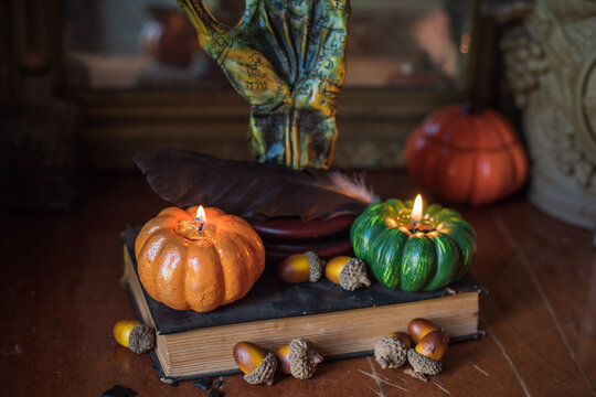 Cozy Halloween home decor with burning pumpkin candles, handmade heart candle, vintage books and mystical props on table