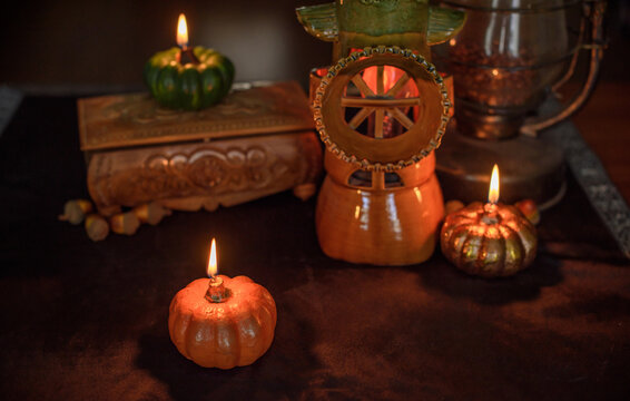 Cozy Halloween home decor with burning pumpkin candles, handmade heart candle, vintage books and mystical props on table