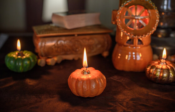 Cozy Halloween home decor with burning pumpkin candles, handmade heart candle, vintage books and mystical props on table