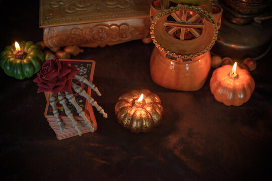 Cozy Halloween home decor with burning pumpkin candles, handmade heart candle, vintage books and mystical props on table