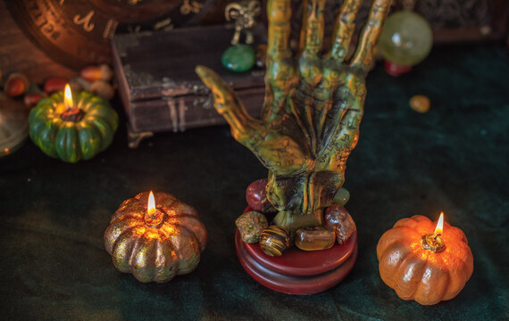 Cozy Halloween home decor with burning pumpkin candles, handmade heart candle, vintage books and mystical props on table