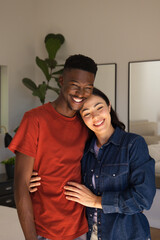 Fototapeta premium Diverse couple standing in bedroom, woman leaning on man's shoulder, wearing denim, with fig plant
