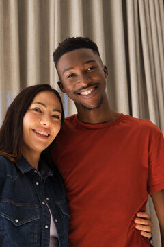 Diverse couple standing and leaning in studio before curtain, denim jacket and rust shirt