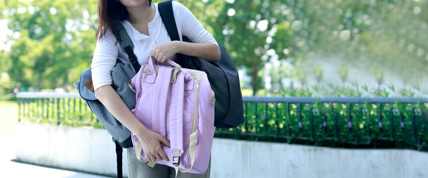 Female student is struggling carry friend's bulky heavy backpack that she was asked to hold the awkward load makes it difficult for her to get around and reach her classroom : Copy Space
