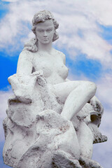 Ancient statue of Aphrodite, Greek goddess of love and beauty, against a dramatic blue sky with white clouds. © zwiebackesser