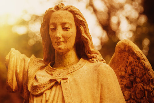 Guardian angel statue illuminated by warm golden sunlight, symbol of divine protection, faith, hope and spiritual guidance.