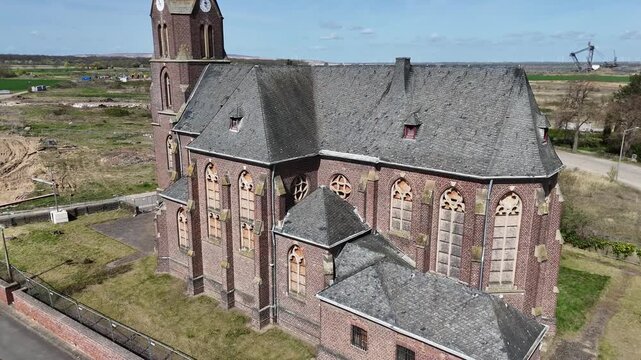 boarded gothic windows mark deconsecrated st albanus leonhardus church apse manheim alt kerpen germany slate roof brick facade bucket wheel excavator distant hambach lignite mine aerial drone close up