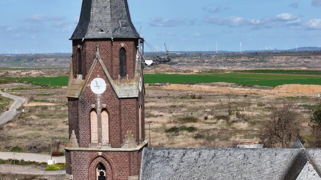 clock tower st albanus leonhardus church rises brick gothic spire manheim alt kerpen germany bucket wheel excavator works hambach lignite mine wind turbines line horizon aerial drone close up