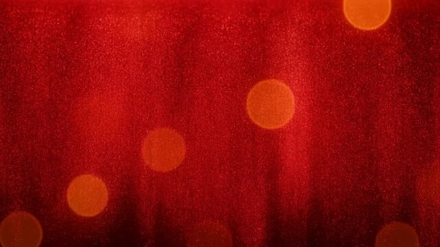 Glowing orange bokeh lights and sparkling particles on dark red abstract background