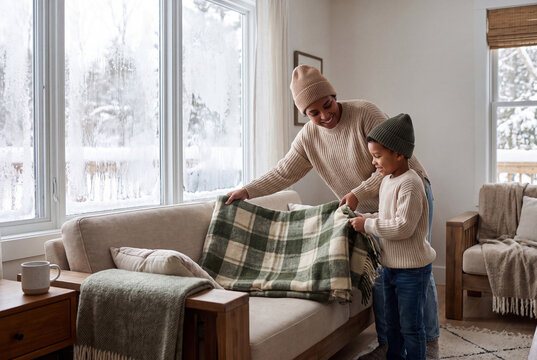 Mother and child arranging a blanket beside snowy window