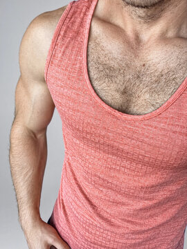 Muscular man in salmon pink sleeveless tank top close up torso