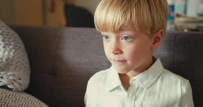 Young boy pulling out his own loose baby tooth with a string