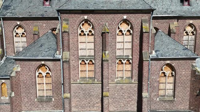 brick church facade boarded windows slate roof dormers chain link fence surrounds manheim alt kerpen germany deconsecrated parish church demolished village empty grounds