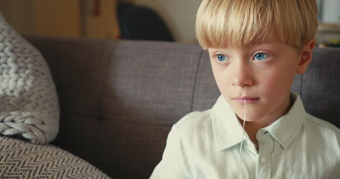 Young boy pulling out his own loose baby tooth with a string
