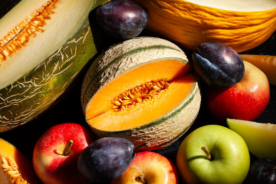 various melons sliced on black background