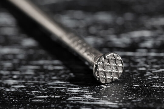 one nail head on black wood background macro