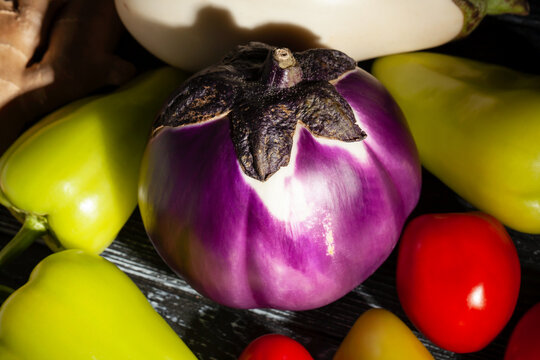 round purple eggplant vegetable mix on black wood background