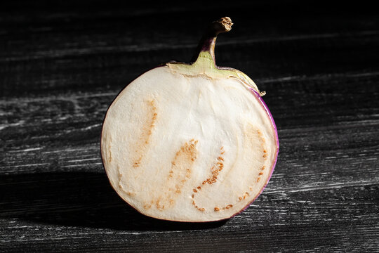sliced round purple eggplant on black wood background