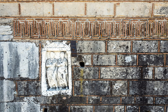 Detail of 13th century Panagia Mermbaka in Argolida, Greece, showing a carved marble relief of two standing figures embedded in Byzantine brick and stone masonry beneath a geometric frieze.