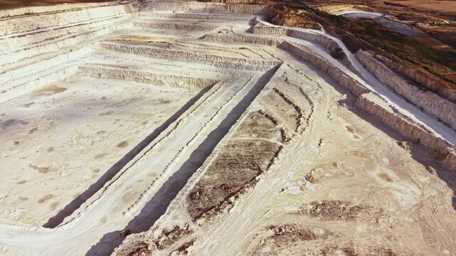 A large limestone quarry is visible from above, showing layers of rock and dirt. Mining equipment is located on the site. The landscape shows signs of extraction activities.