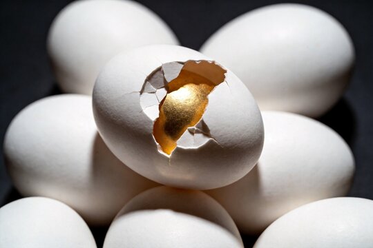 Cracked golden egg among white eggs revealing a golden interior. Concept of breakthrough, hidden potential, innovation, creativity and transformative ideas.