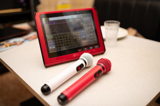 カラオケルームのテーブルに置かれた2本のマイクと選曲用タブレット