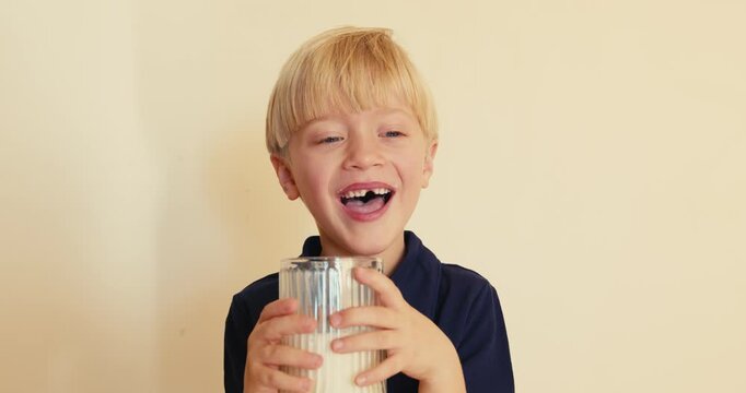Cute blond boy drinking milk laughing