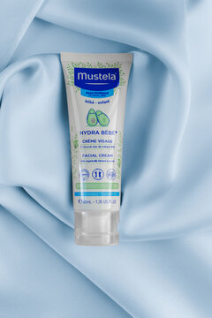 Lviv Ukraine - September 12, 2026: Mustela Hydra Bebe facial cream tube for baby skin care on blue silk fabric background