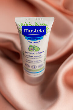 Lviv Ukraine - September 12, 2026: Mustela Hydra Bebe facial cream tube for baby skin care on pink silk fabric background