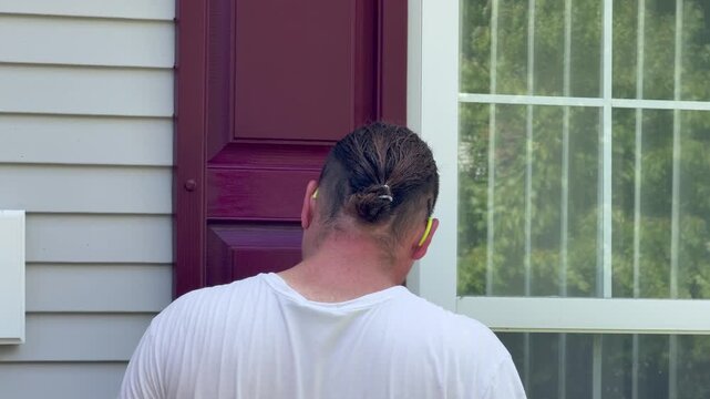 Handyman painting the shutters on a house red with a paintbrush