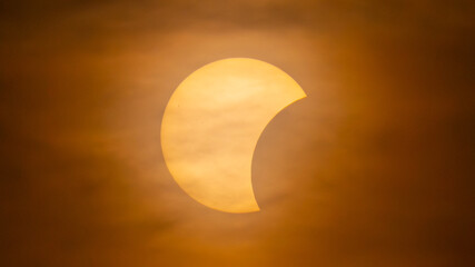 Partial solar eclipse on September 12, 2026, with the Moon visibly covering a significant portion of the Sun. The Sun appears as a bright orange crescent against a dark sky.  © coffeinlix 