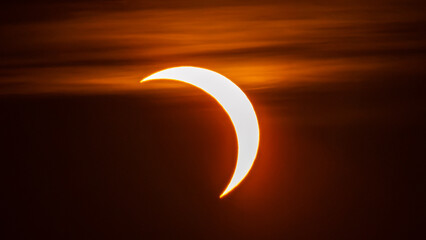 Partial solar eclipse on September 12, 2026, with the Moon visibly covering a significant portion of the Sun. The Sun appears as a bright orange crescent against a dark sky.  © coffeinlix 