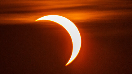 Partial solar eclipse on September 12, 2026, with the Moon visibly covering a significant portion of the Sun. The Sun appears as a bright orange crescent against a dark sky.  © coffeinlix 
