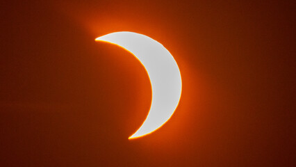 Partial solar eclipse on September 12, 2026, with the Moon visibly covering a significant portion of the Sun. The Sun appears as a bright orange crescent against a dark sky.  © coffeinlix 