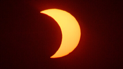 Partial solar eclipse on September 12, 2026, with the Moon visibly covering a significant portion of the Sun. The Sun appears as a bright orange crescent against a dark sky.  © coffeinlix 