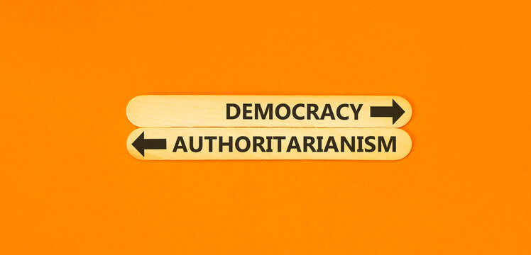Democracy or authoritarianism words symbol. Concept words Democracy Authoritarianism on beautiful wooden sticks. Beautiful orange background. Business democracy authoritarianism concept. Copy space