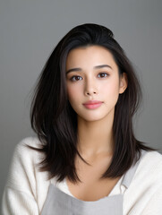 Fototapeta premium Young Asian woman with smooth skin, natural makeup, straight dark hair, wearing white sweater, neutral background