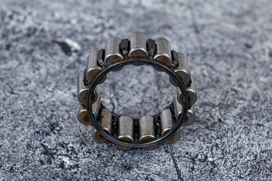 Industrial cylindrical roller bearing standing upright on rough textured concrete surface.