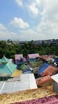 Cinematic FPV drone flight over colorful rooftops in Jodipan Village, Malang, Indonesia, revealing densely packed painted houses and vibrant urban architecture.