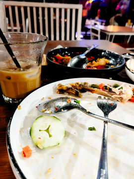 Top view of messy empty plates with food leftovers and iced coffee on a wooden table