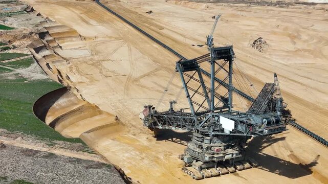 giant bucket wheel excavator carves layered sand terraces beside green farmland edge lignite pit steel lattice boom cables drone aerial footage hambach coal mine germany surface mining brown coal