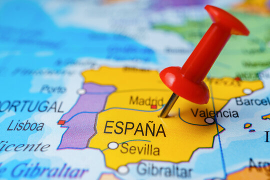Red pushpin identifying spain on a detailed geographic map, indicating travel destination, location, and iberian peninsula