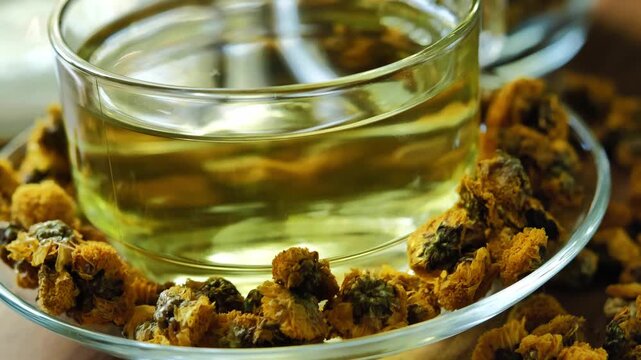 Dried chrysanthemum flowers displayed with a glass of chrysanthemum tea, highlighting a traditional floral herbal beverage