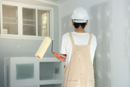 painter man, brush in hand for products to restore and paint the wall, indoor the building site of a house, wall during painting, renovation, painting, contractor, Architect, construction worker