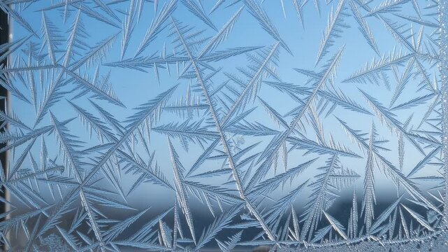 Frost crystals forming on window glass against a blue sky.